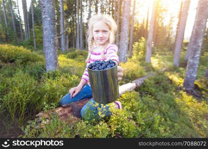 hiking in the mountains. girl holding a cup of blueberries
