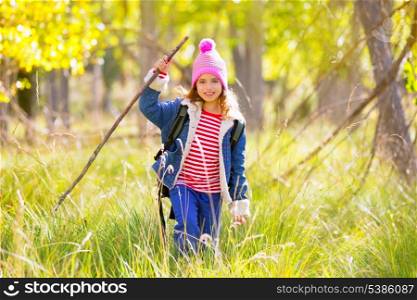 Hiking kid girl with backpack in autum poplar trees forest and walking stick