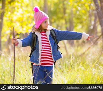 Hiking kid girl with backpack pointing finger in autum poplar trees forest