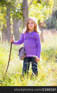 Hiking kid girl with walking stick in autum poplar trees forest