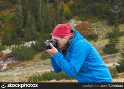 hiking man in nature taking photos with digital photo camera of mountains landscape