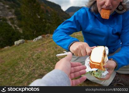 hiking man slice tasty cheese on picnic and share with friends
