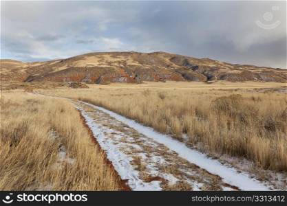 hiking trail on a ranch road with snow and footprints - Red Mountain Open Space in northern Colorado (Larimer County), fall scenery with dry grass