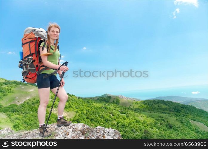 Hiking woman with backpack. Happy young hiking woman with backpack on the top of green mountain