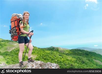 Hiking woman with backpack. Happy young hiking woman with backpack on the top of green mountain