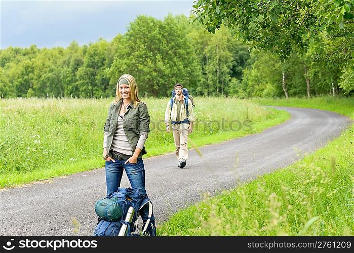 Hiking young couple backpack tramping on asphalt road countryside