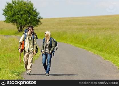 Hiking young couple backpack tramping on asphalt road sunny countryside