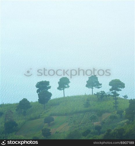 Hilltop fields in mist with Lake Atitlan in Guatemala