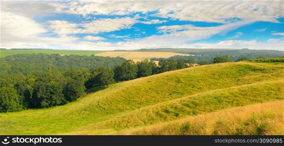 Hilly field. Picturesque spring field. Agricultural field. Wide photo.
