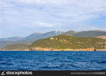 Hilly greek coast of the Gulf of Corinth in sunny day. Old lighthouse building and many wind farms. Lighthouse on a Hilly Shore and Wind Farms