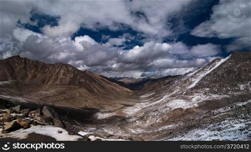 Himalaya high mountain landscape panorama with dramatic cloudy sky near Khardung La pass. India, Ladakh, Altitude 5600 m.