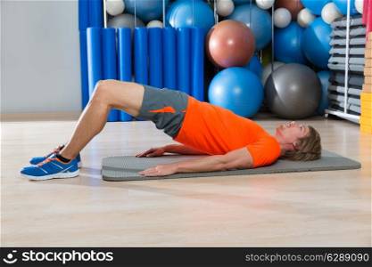 hip lift with blond man at gym workout with swiss ball background