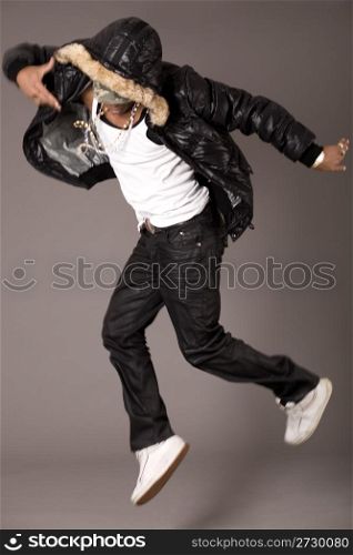 Hip pop dancer jumping on grey background