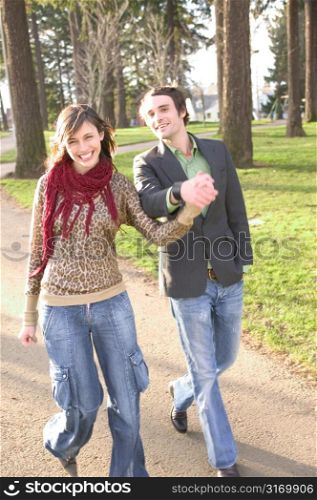 Hip Urban Couple Walking Together Through A City Park And Smiling