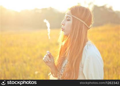 Hippie beautiful woman blowing flower on the golden meadow