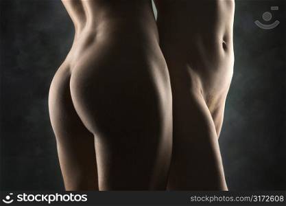 Hips and buttocks of nude Hispanic and Caucasian women standing together.