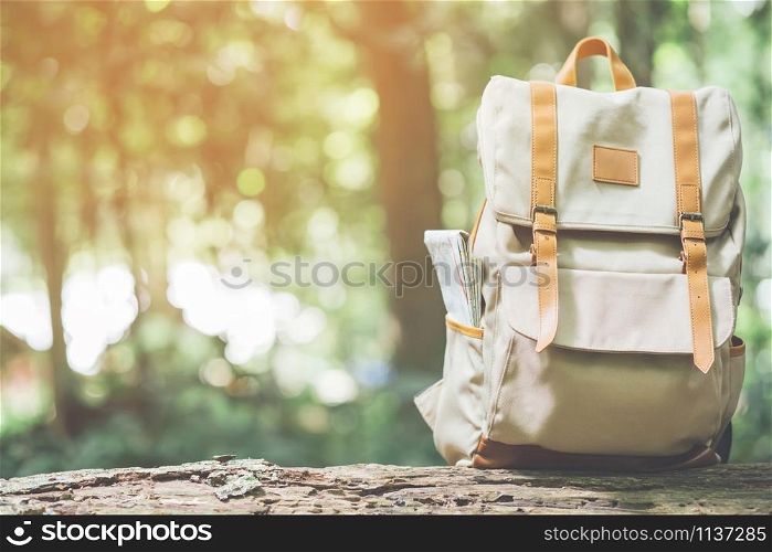 Hipster Backpack walk in the forest Travel accessories and map on Timber lumber log. View from backside tourist traveler bag on background Forest tree. concept holidays Travel.