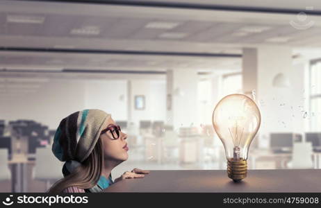 Hipster girl looking from under table. Attractive student girl in red glasses peeping from under table