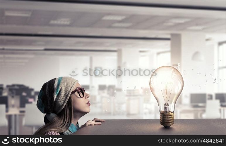 Hipster girl looking from under table. Attractive student girl in red glasses peeping from under table