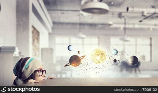 Hipster girl looking from under table. Attractive student girl in red glasses peeping from under table