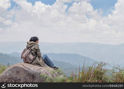 Hipster girl sitting in rocky of mountain . Hipster girl with backpack sitting in a rocky top of the mountain against the blue of sky