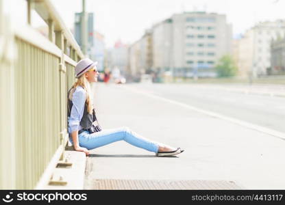 Hipster girl sitting on city street