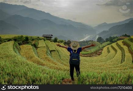 Hipster girl standing behind leinster arms. The atmosphere rice terraces in the evening. There are mountains behind the scenes. at Mu Cang Chai in Vietnam.