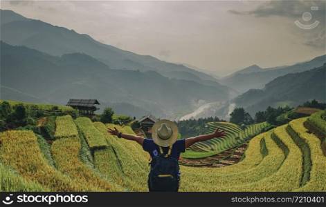 Hipster girl standing behind leinster arms. The atmosphere rice terraces in the evening. There are mountains behind the scenes. at Mu Cang Chai in Vietnam.