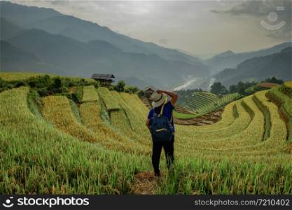 Hipster girl standing holding a hat. The atmosphere rice terraces in the evening. There are mountains behind the scenes. at Mu Cang Chai in Vietnam.