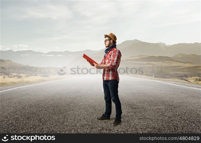 Hipster guy read book. Hipster guy with book in hands on asphalt road