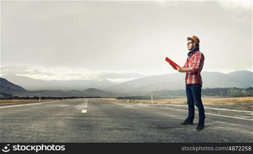 Hipster guy read book. Hipster guy with book in hands on asphalt road
