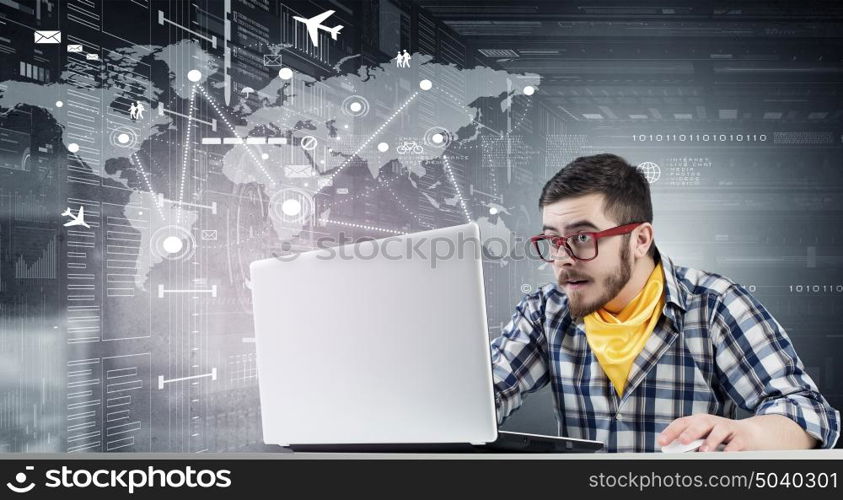 Hipster guy use laptop. Young emotional guy in red glasses surfing the Internet