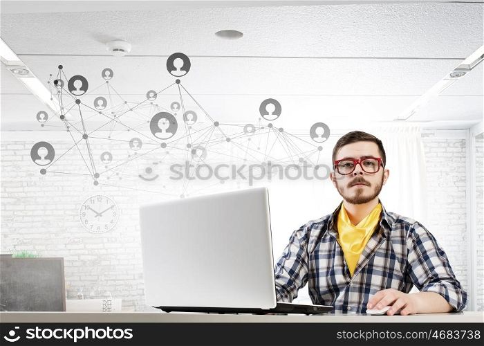 Hipster guy use laptop. Young handsome guy in red glasses surfing the Internet