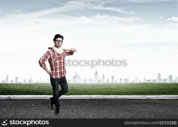 Hipster guy with bat. Young hipster guy with bat on asphalt road