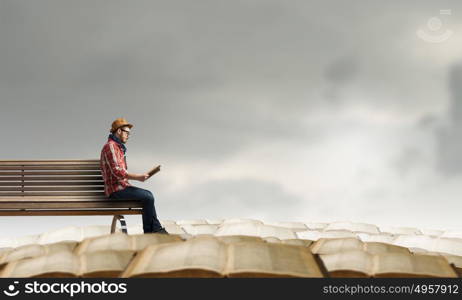 Hipster guy with book in hands. Hipster guy with book in hands sitting on wooden bench