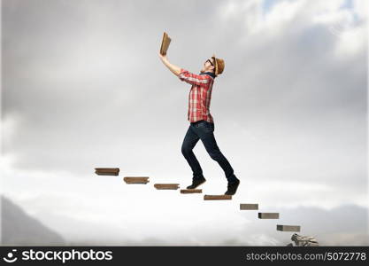 Hipster guy with book in hands. Hipster guy with book in hands walking steps of books