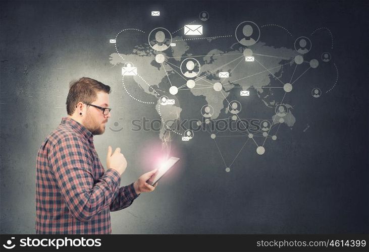 Hipster guy with tablet device. Young thoughtful man in checked shirt using tablet pc