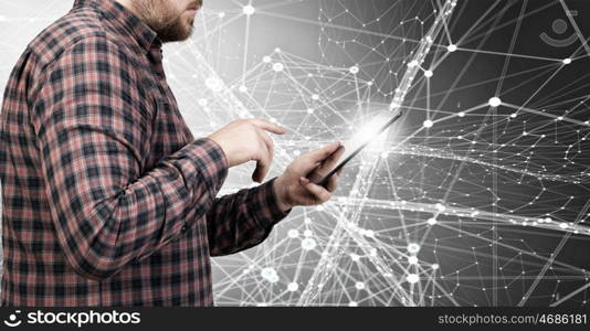 Hipster guy with tablet device. Young thoughtful man in checked shirt using tablet pc