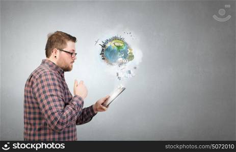 Hipster guy with tablet device. Young thoughtful man in checked shirt using tablet pc. Elements of this image are furnished by NASA
