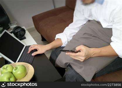 hipster hand using digital tablet docking keyboard and mobile payments online business,omni channel,sitting on sofa in living room,green apples in wooden tray