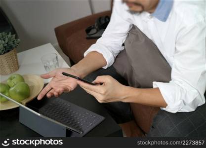 hipster hand using digital tablet docking keyboard and mobile payments online business,omni channel,sitting on sofa in living room,green apples in wooden tray