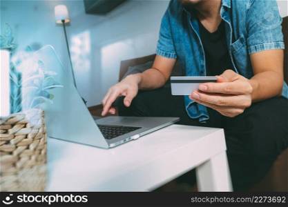 hipster hand using laptop compter,holding cradit card payments online shopping or business,sitting on sofa in living room,green apples in wooden tray,filter