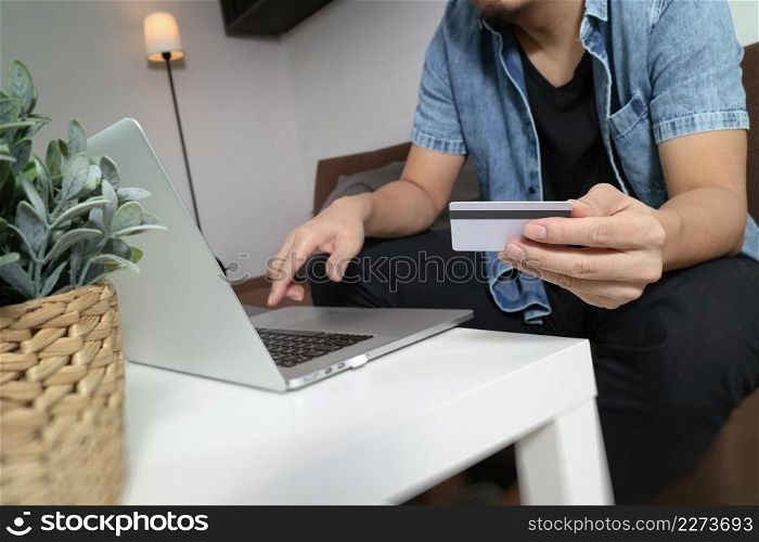 hipster hand using laptop compter,holding cradit card payments online shopping or business,sitting on sofa in living room,green apples in wooden tray