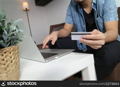hipster hand using laptop compter,holding cradit card payments online shopping or business,sitting on sofa in living room,green apples in wooden tray