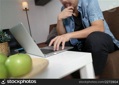 hipster hand using laptop compter payments online business,sitting on sofa in living room,green apples in wooden tray,work at home concept,