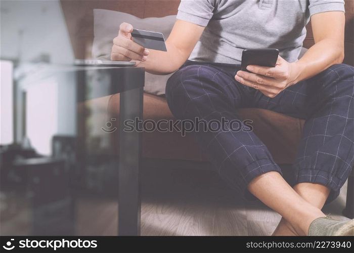 hipster hand using smart phone and laptop compter,digital tablet docking keyboard,holding cradit card payments online business,sitting on sofa in living room,work at home concept,filter effect