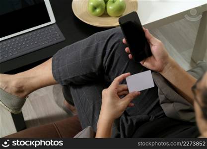 hipster hand using smart phone and laptop compter,holding cradit card payments online business,sitting on sofa in living room,green apples in wooden tray