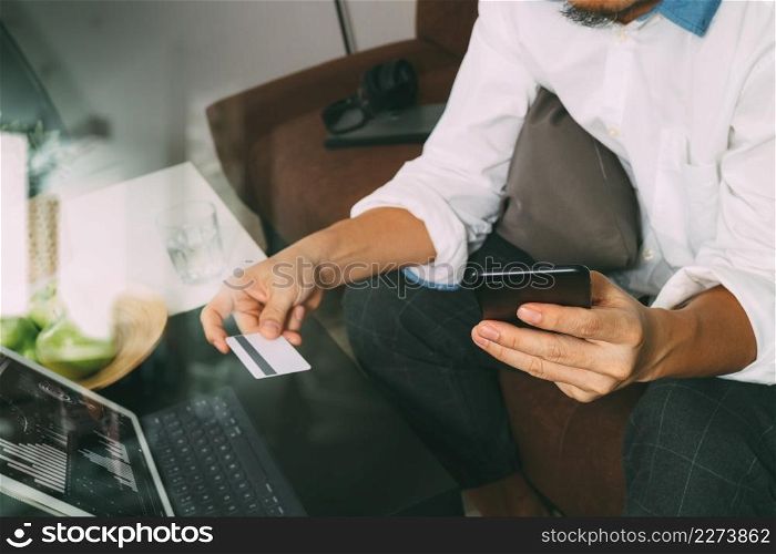 hipster hand using smart phone and laptop compter,holding cradit card payments online business,sitting on sofa in living room,green apples in wooden tray,filter