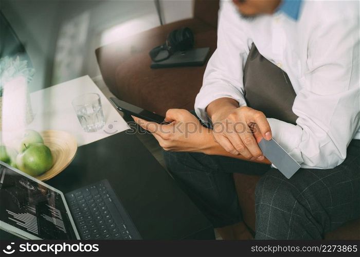 hipster hand using smart phone and laptop compter,holding credit card payments online business,sitting on sofa in living room,green apples in wooden tray,filter