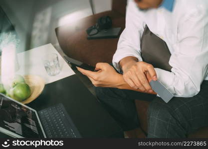 hipster hand using smart phone and laptop compter,holding credit card payments online business,sitting on sofa in living room,green apples in wooden tray,filter